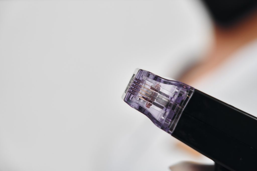 Close-up view of a microneedling device being held in a clinic setting