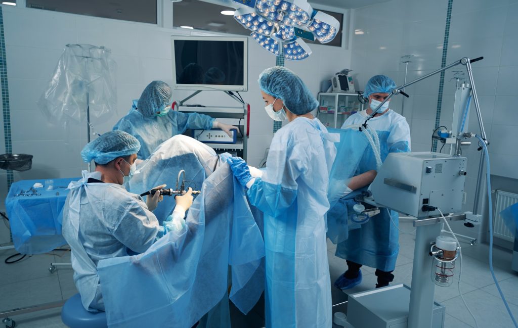 Four surgery specialist in operating theater treating patient